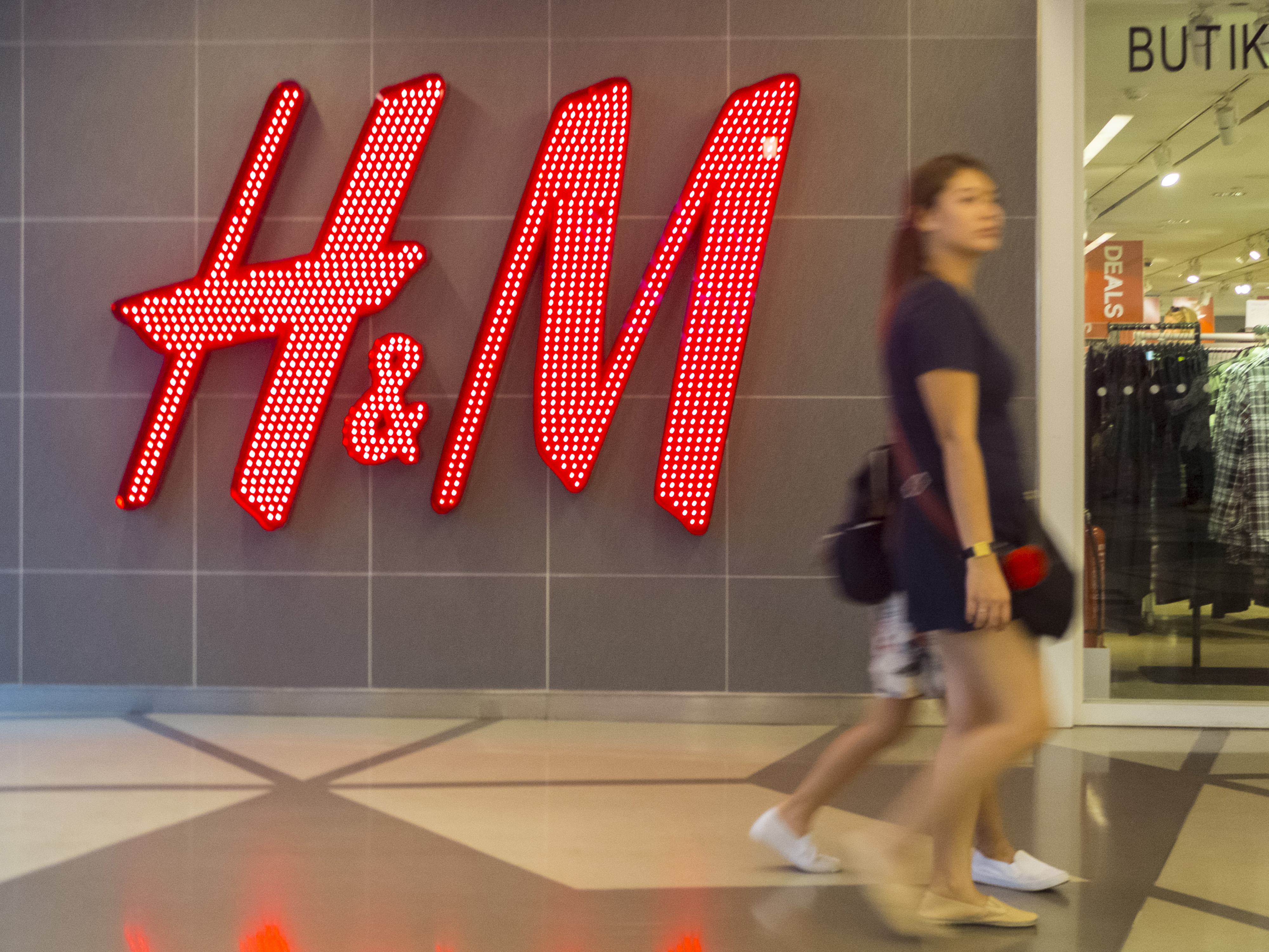 A woman seen walking in front of the H&M shop. Malaysia...