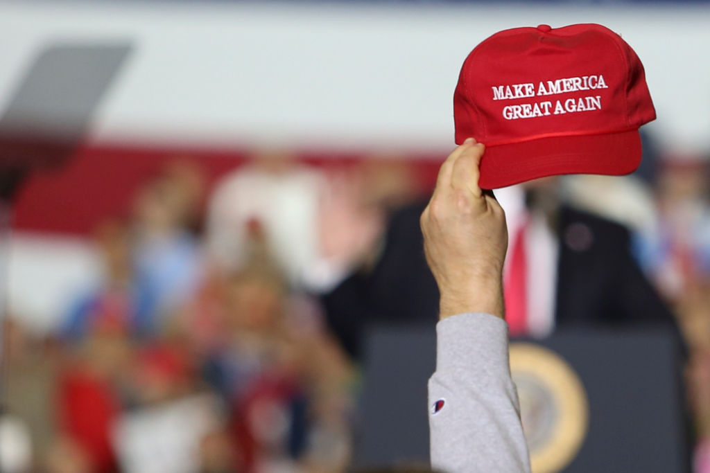 A supporter seen raising a caps writting on it 'Make America...