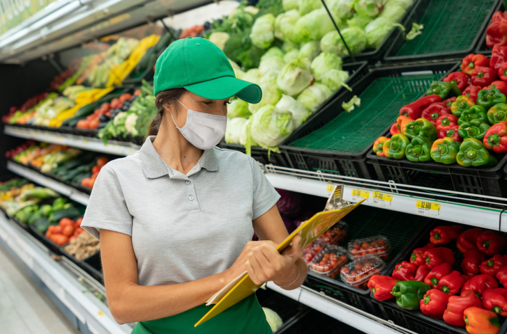 Woman wearing a facemask while working at the grocery store making the inventory