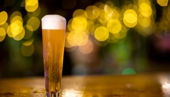 Glass of light beer on a golden color pub.