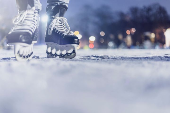 Close-up of feet with ice skates on frozen lake. Bokeh in the background. Wintertime