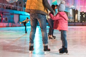 cropped shot of father and daughter holding hands while standing together on skating rink