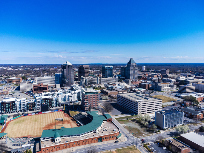 Aerial view of Greensboro, North Carolina showcasing the downtown skyline under a clear blue sky.
