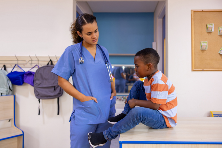 Injured boy talking to the nurse at the school while in pain